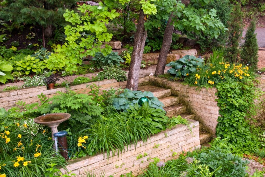 A garden with a stone retaining wall and landscaped flowers.