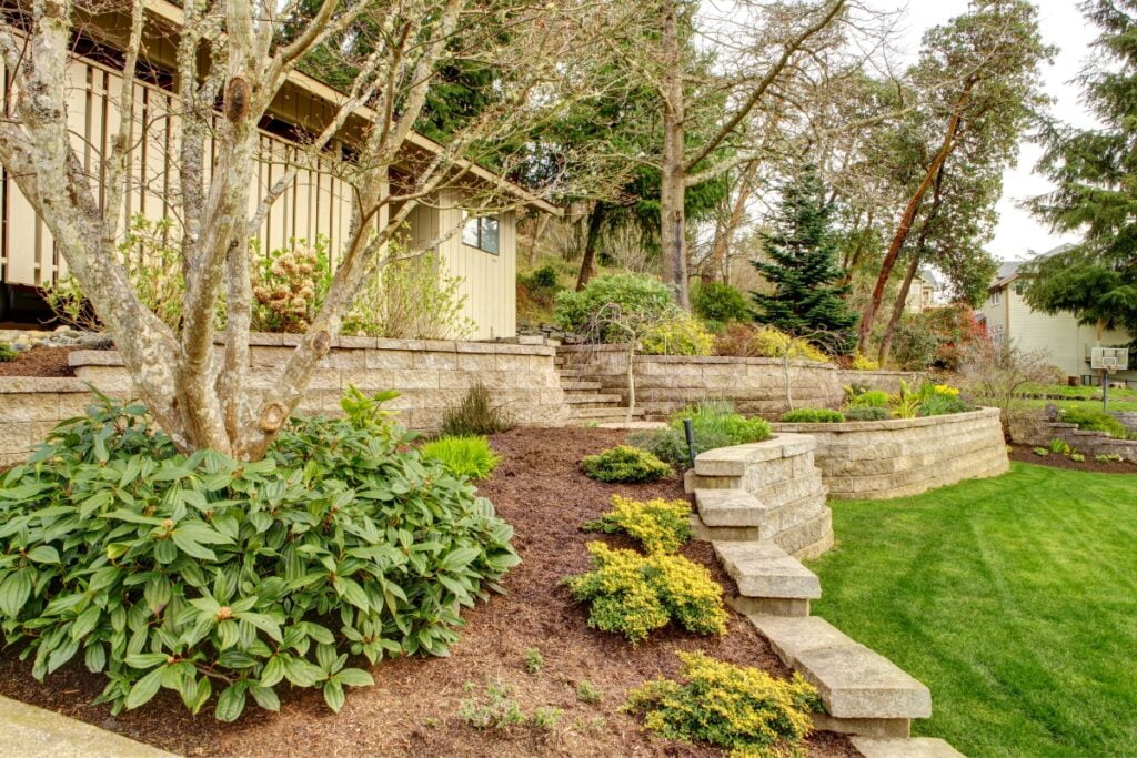 A backyard with a landscaping design featuring a beautiful stone retaining wall.