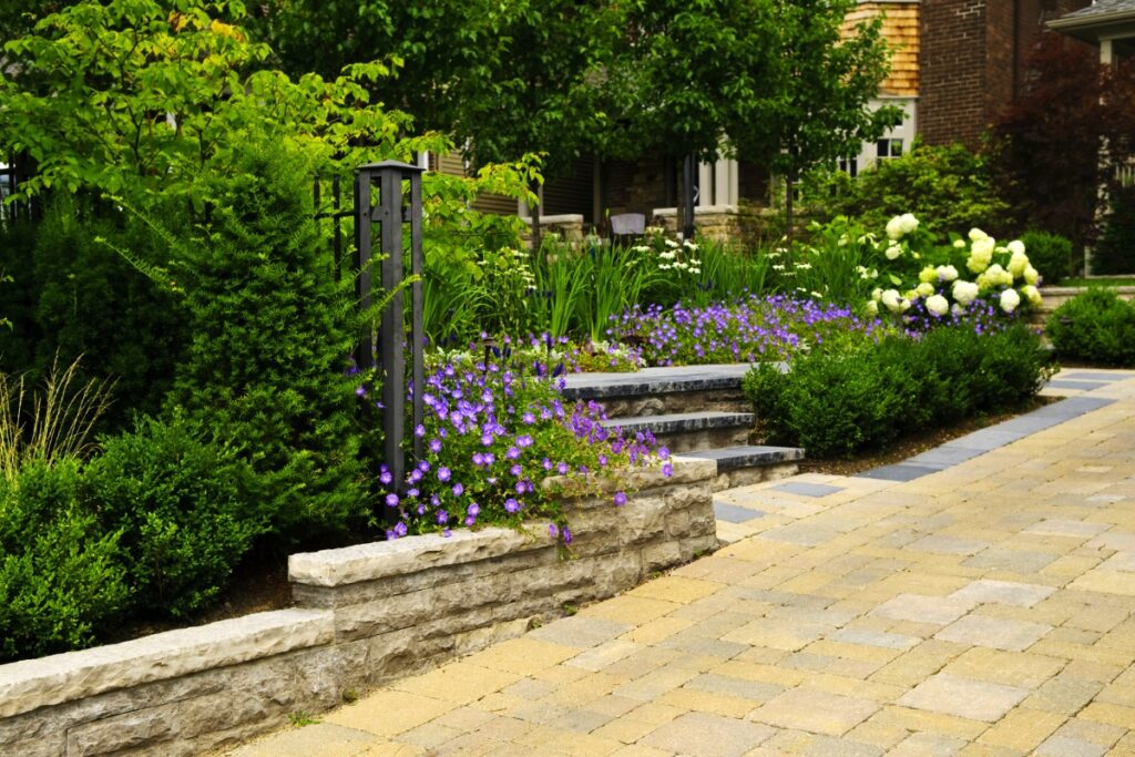 A stone walkway leading to a flower garden with landscaping.