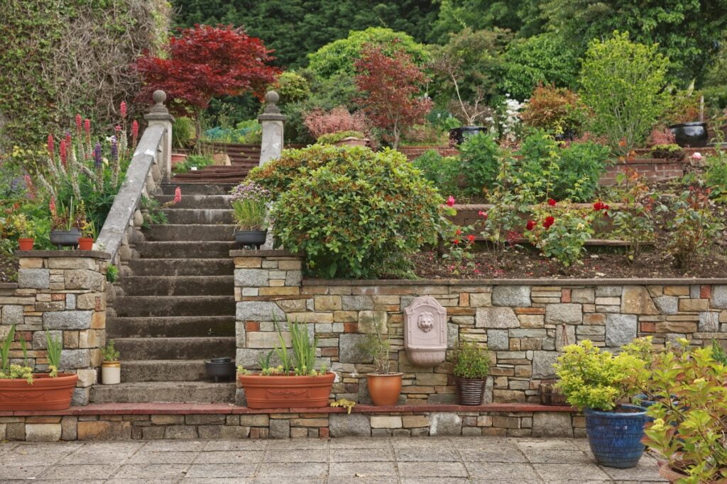 A landscaped garden with retaining walls and potted plants.