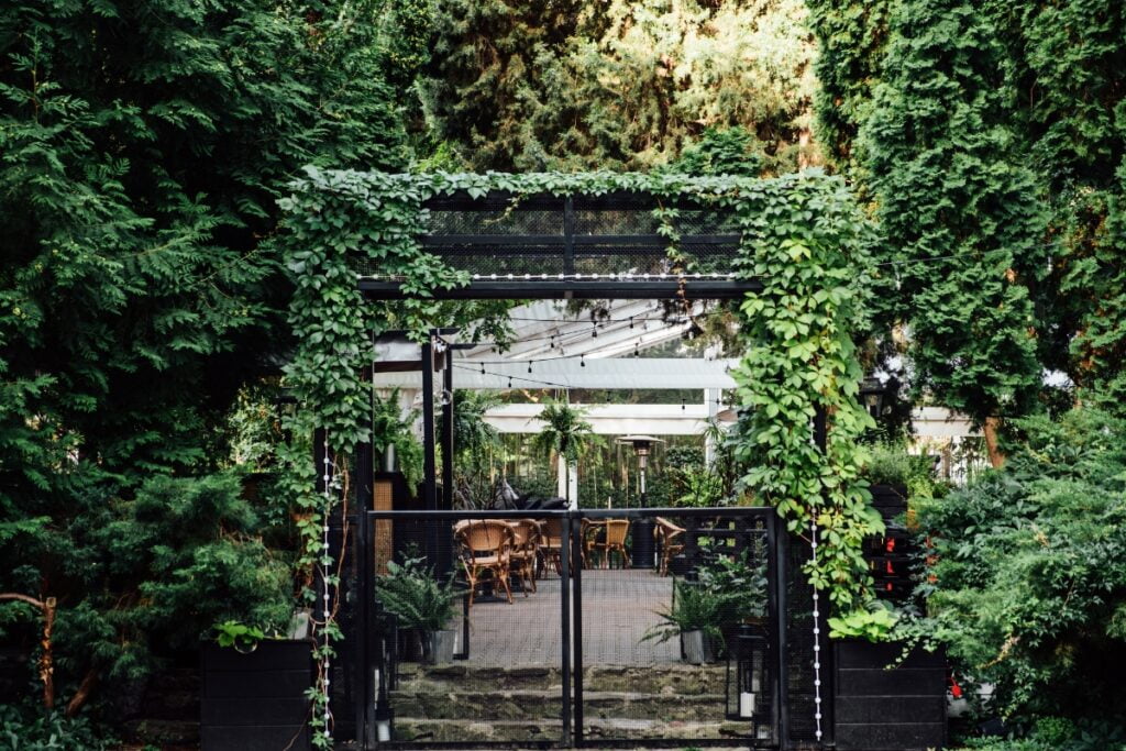 The entrance to a restaurant is adorned with lush greenery, showcasing current landscape architecture trends.