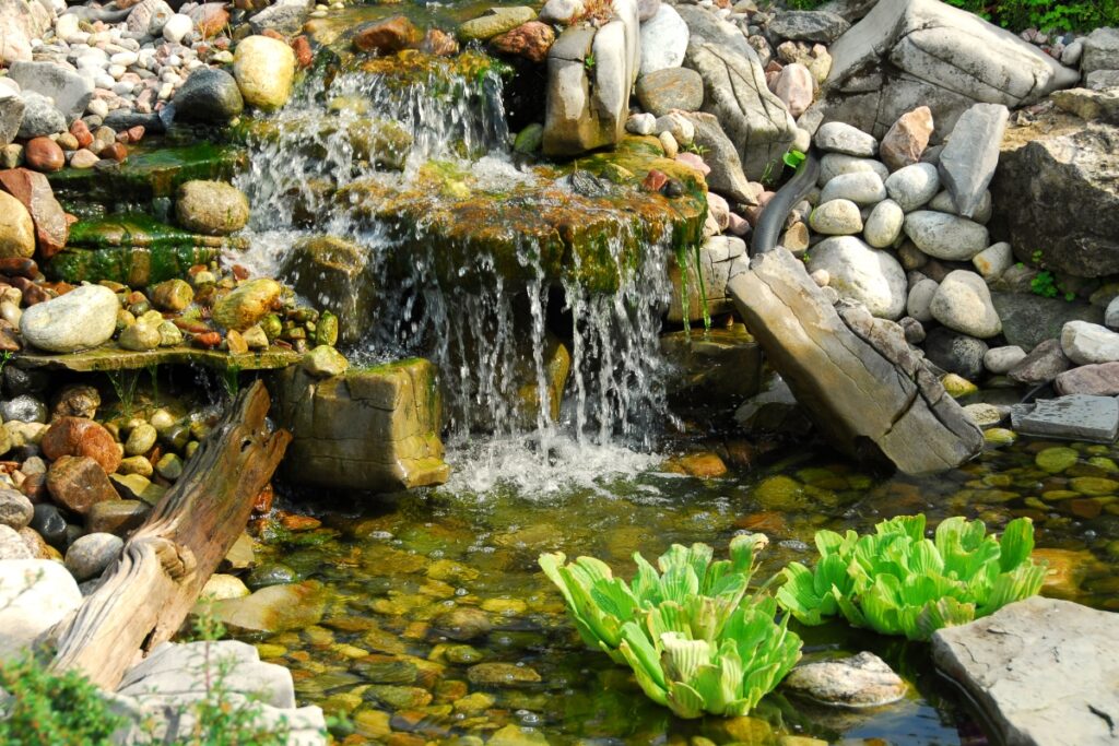 A garden waterfall surrounded by boulders and plants.