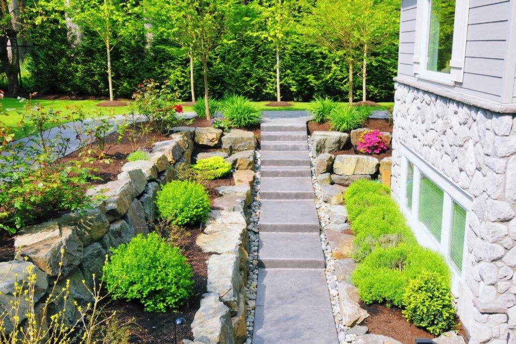 A stone walkway leading to a house creating an aesthetically pleasing front yard landscape design.