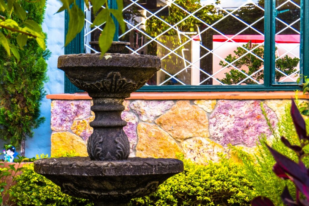 A front yard landscape design featuring a fountain in front of a house.