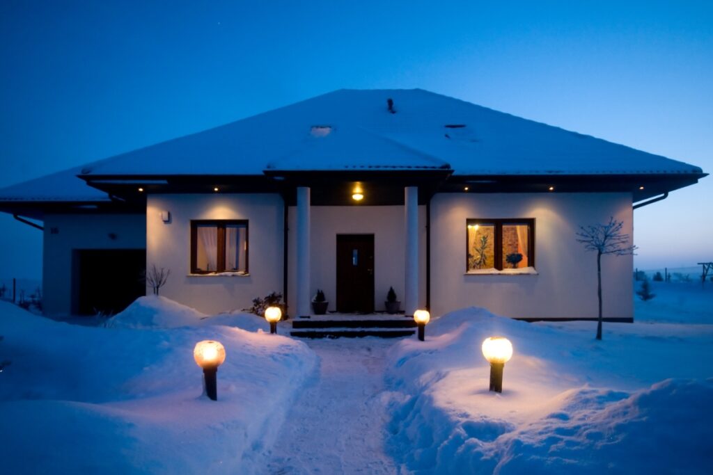 A beautifully illuminated house stands out at night, glowing against the backdrop of serene snow.