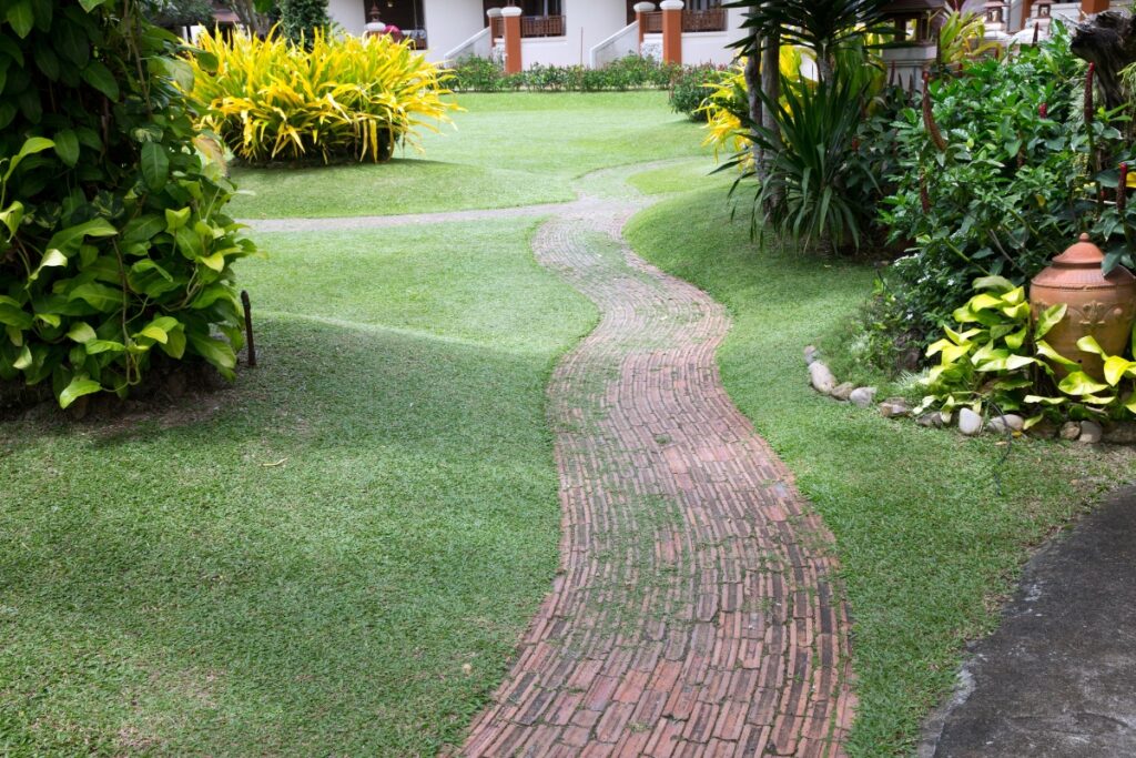 Building a brick pathway in a lush green garden.