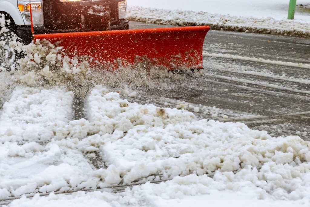 A snow plow is being used to clear snow from a street during winter.