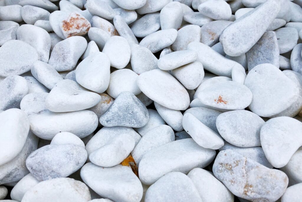 A pile of white pebbles used as a garden stone border on the ground.