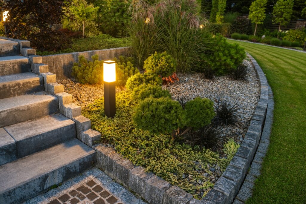 A garden with a stone border and steps leading up to a stone walkway.