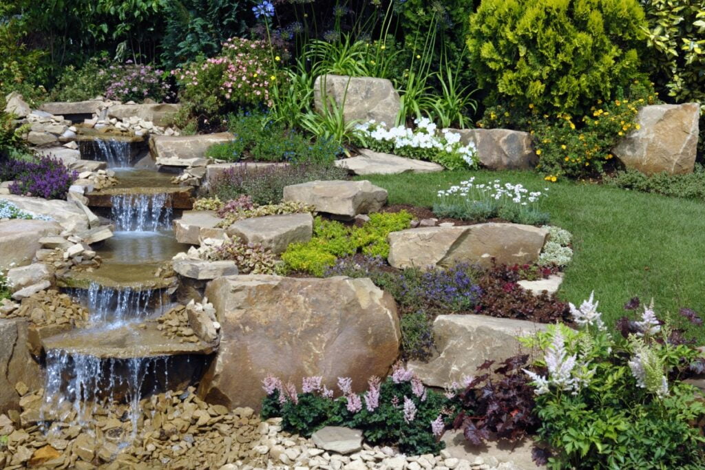 Water Feature Trends: Innovative Ideas to Transform Your Outdoor Space 7 A garden with a stunning waterfall as the central water feature, accentuated by strategically placed rocks for added natural beauty.