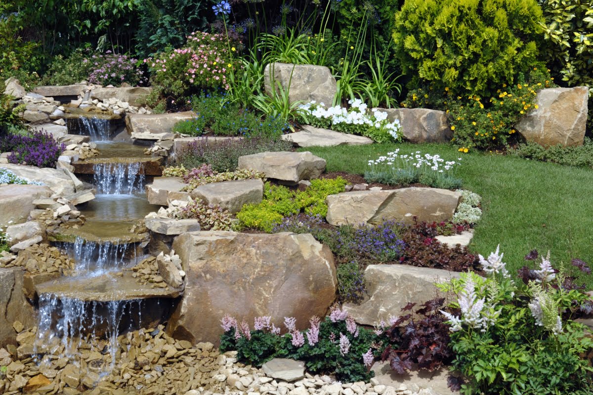 A garden with a stunning waterfall as the central water feature, accentuated by strategically placed rocks for added natural beauty.