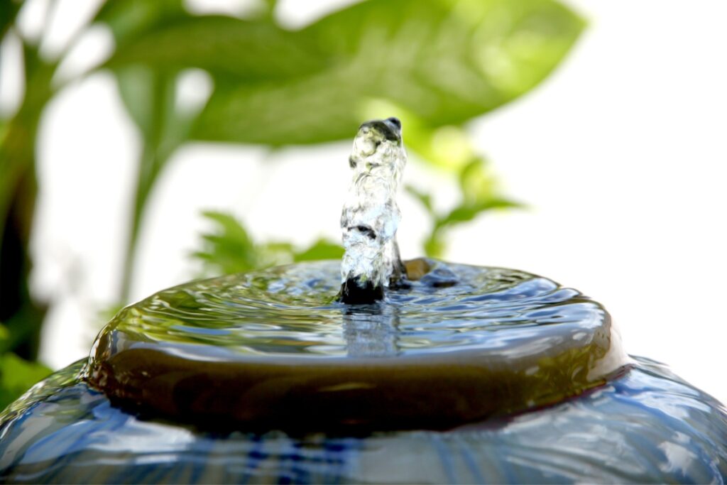 A plant-filled pot with a serene water fountain as a modern water feature.