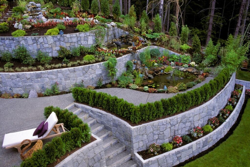 Terraced garden with stone walls, a variety of plants, a small pond, and outdoor living trends.