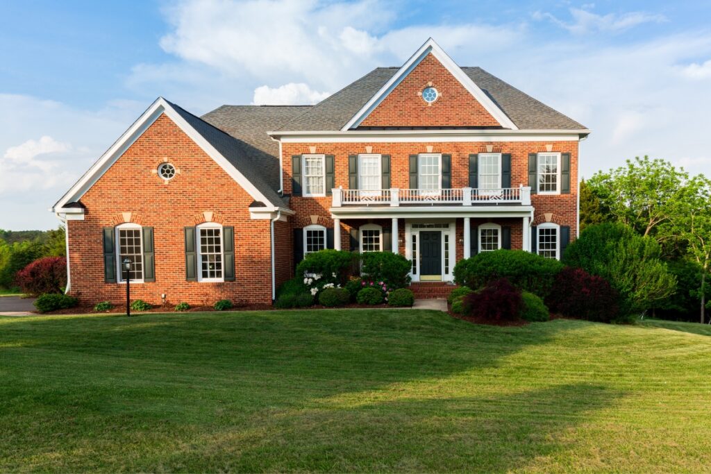 A brick home with a green lawn featuring yard grading.