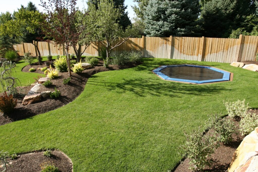 A backyard with yard grading, a trampoline, and a wooden fence.