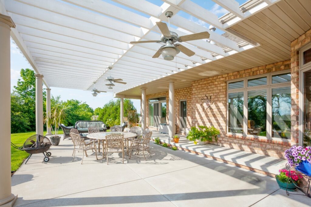 Spacious patio with outdoor furniture, ceiling fans, and a sunny sky optimized with hardscape design.