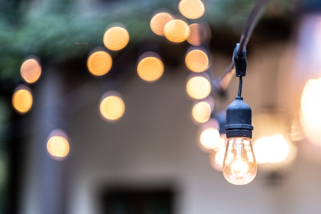 Close-up of a string of outdoor lighting, with one light bulb in focus and several others blurred in the background, creating a bokeh effect.