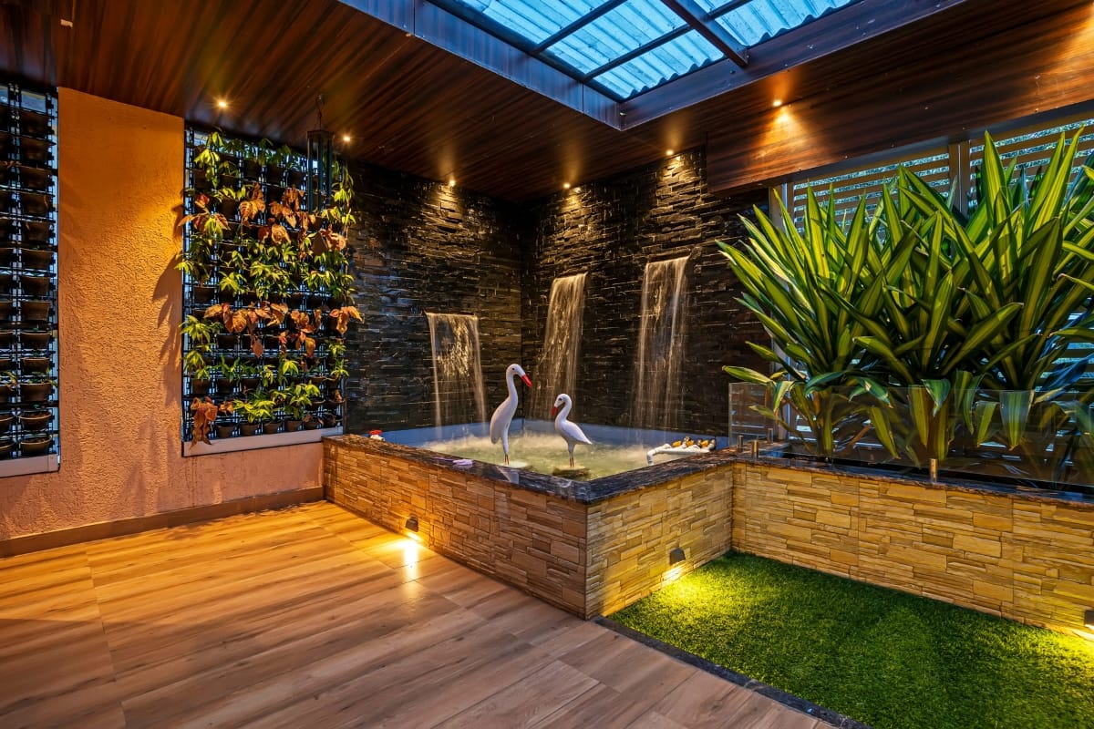 Commercial Water Features in Smyrna: How They Help Attract More Customers 3 Modern indoor garden with a small pond, artificial flamingos, vertical plant wall, and a fountain under a glass roof with wooden and stone accents, showcasing elegant commercial water features.
