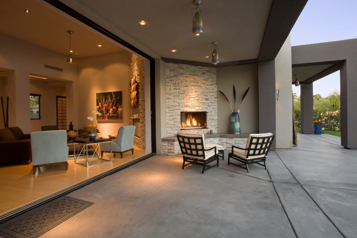 Fire Features in Buckhead: Why Commercial Spaces Should Invest 2 Modern home with open living room and patio, featuring stylish fire features like a stone fireplace, two chairs, and large glass doors leading outside.