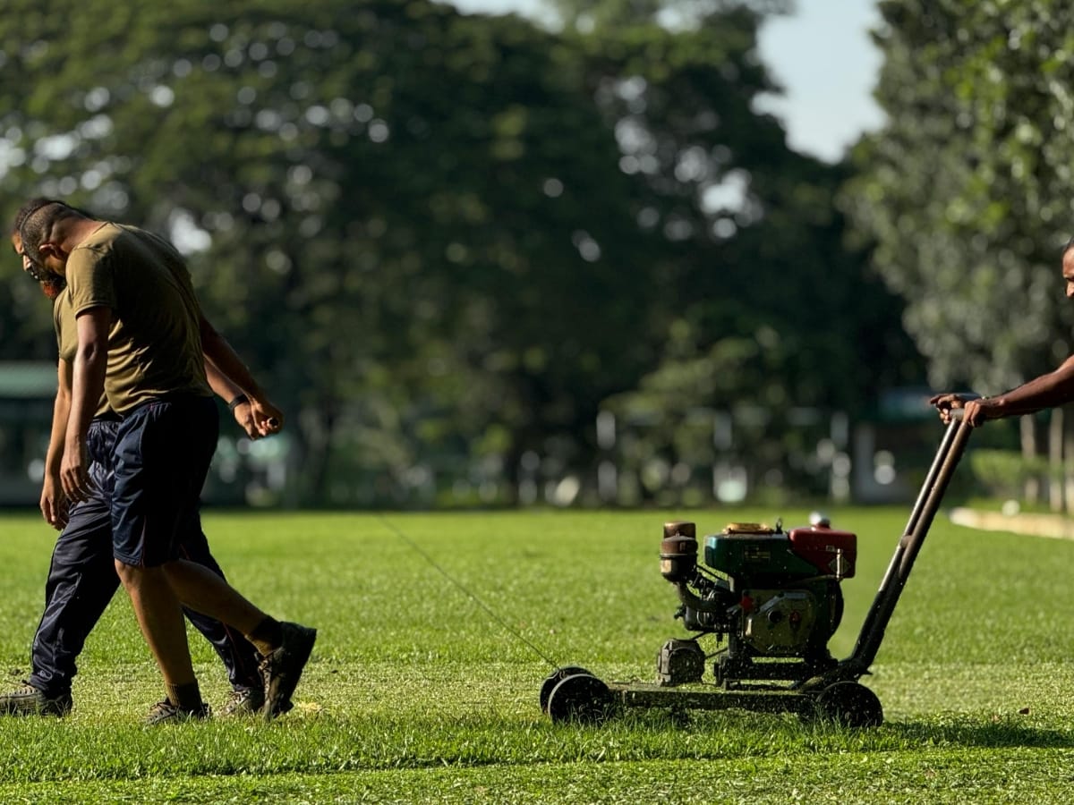 The Role of Commercial Grading Services in Smyrna for Business Landscaping 1 Two people walk on grass while another person operates a lawn mower on a sunny day, showcasing commercial grading in progress, with trees in the background.