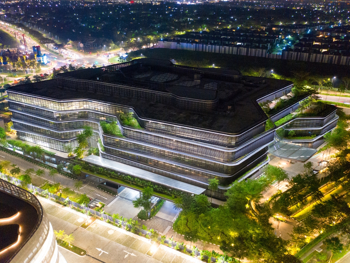 Aerial night view of a modern, multi-story building with illuminated windows and surrounding trees, showcasing refined Commercial Landscape Design in Marietta’s vibrant urban area.