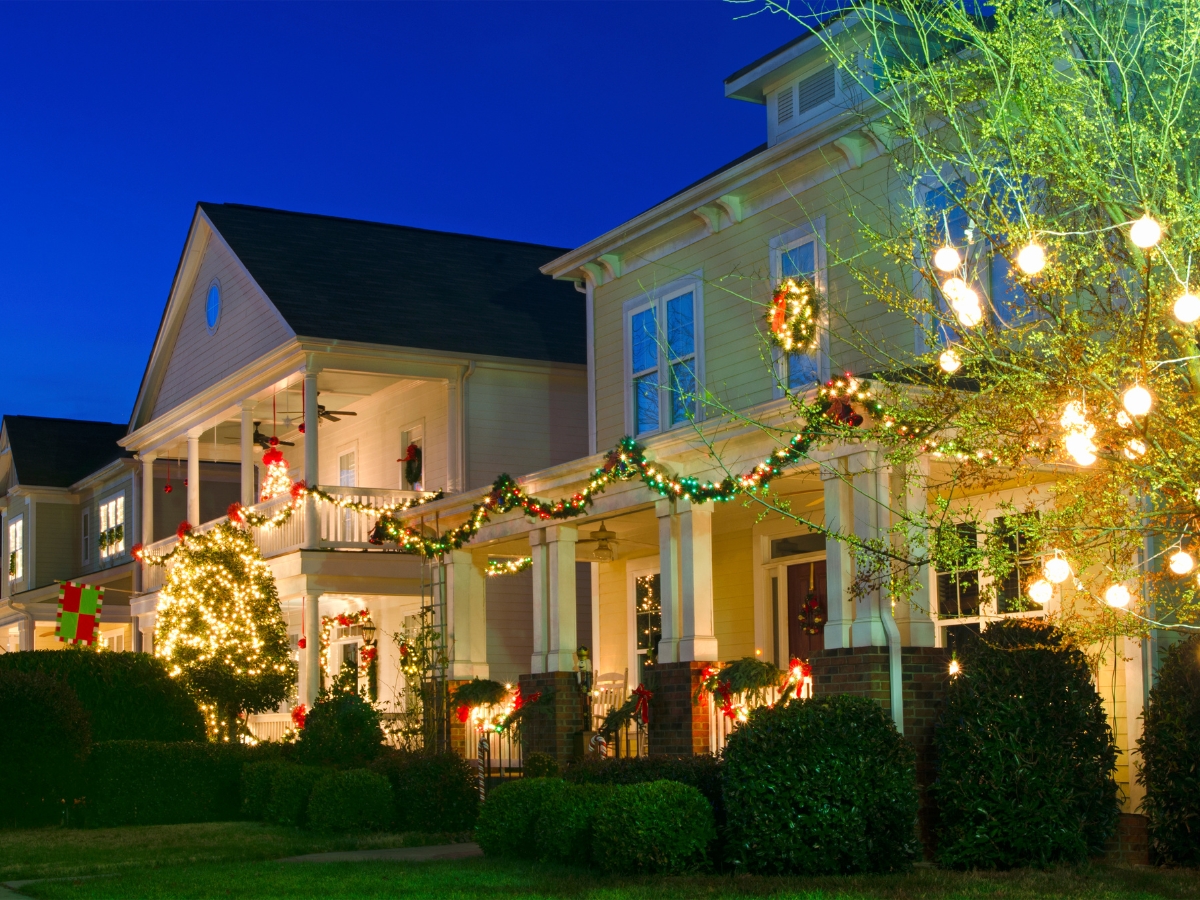 Holiday Landscaping Services Roswell GA Businesses Need 2 Two houses decorated with Christmas lights, wreaths, and garlands at dusk. The front yards showcase lit bushes and festive decorations, beautifully enhanced by Holiday Landscaping Services Roswell.